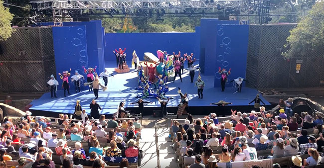 PacRep's Disney's The Little Mermaid on the Outdoor Forest Theater stage, with a full audience under the pines